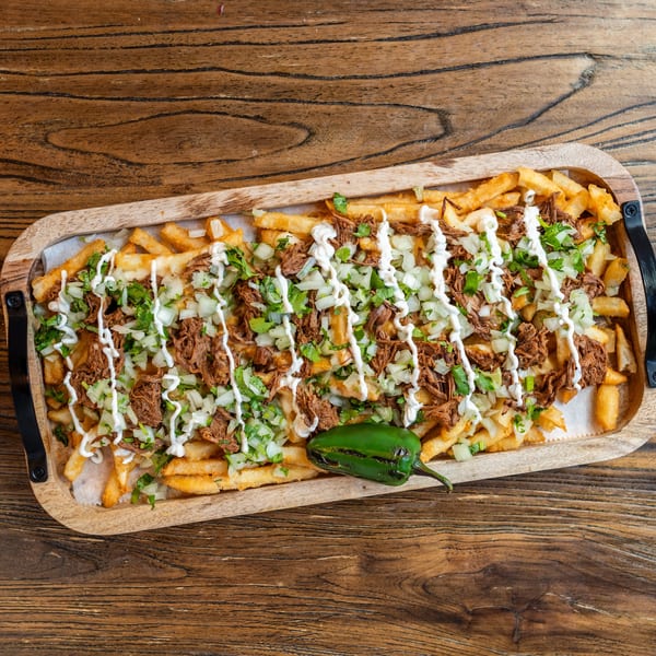 Mexican Mariachi Grill's loaded fries with shredded meat, onions, cilantro, and crema, served with a jalapeño.