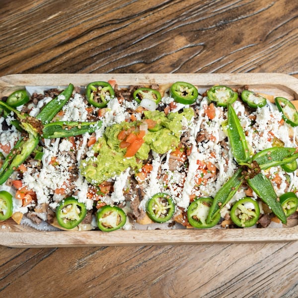 Mexican nachos with meat, guacamole, pico de gallo, sour cream, cheese, and jalapeños.