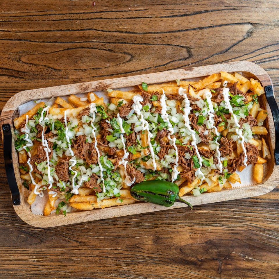 Mexican Mariachi Grill's carne asada fries, topped with shredded beef, onions, cilantro, and crema.